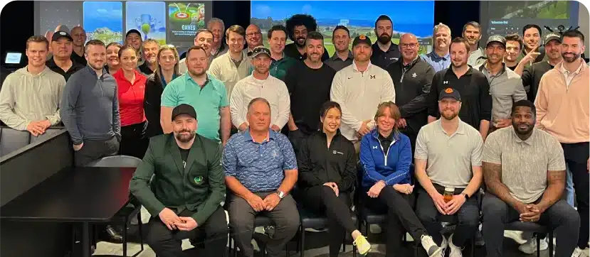 A large group poses in front of TrackMan indoor golf simulator screens at Silverwood’s Golf & Lounge, Kanata.